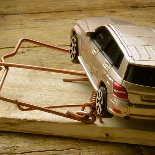 Spielzeugauto in einer Mausefalle als Symbolbild für Betrugsmaschen und gefälschte Angebote im Gebrauchtwagenhandel.